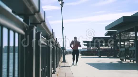 肌肉男在阳光明媚的日子在长廊上笨拙地慢跑视频的预览图