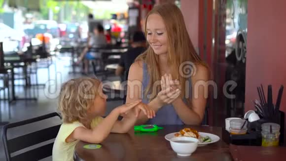 年轻女子和儿子在咖啡馆里用洗手液视频的预览图