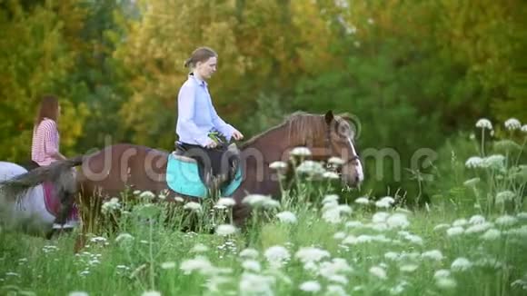 日落时分年轻的妇女骑马穿过草地视频的预览图