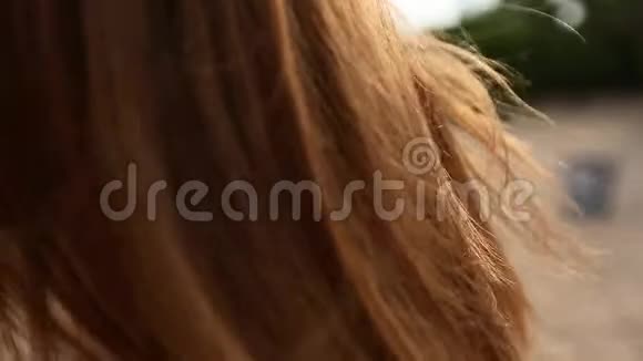 近距离后视红色女人头发在空气中缓慢移动红发女子在沙滩上散步视频的预览图