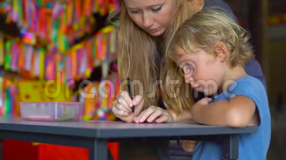 一位年轻女子和她的小儿子参观了KekLokSi佛寺并在彩色纺织品上写下了祝福视频的预览图