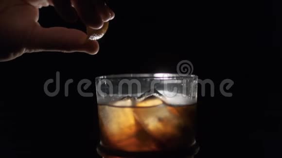 将石灰或柠檬挤在新鲜水果鸡尾酒上威士忌和可乐在深色背景和室内灯光下加冰块视频的预览图