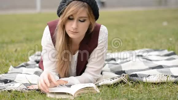 年轻迷人的女人在草地上看书视频的预览图