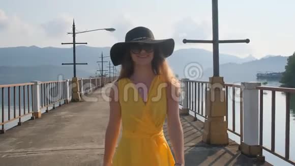 一个穿着黄色衣服的年轻漂亮女孩沿着码头走着海洋海洋视频的预览图
