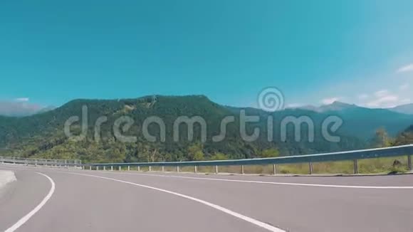 在蓝天上行驶的汽车上一条被树木覆盖的道路和山脉上的风景如画场景山脉视频的预览图