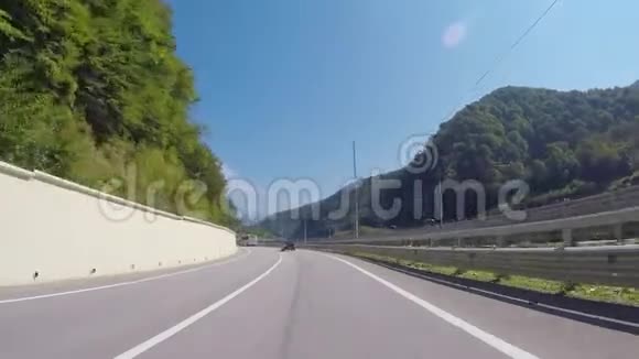 从汽车上行驶到KrasnayaPolyana的高速公路上夏天可以看到蓝天树木和高加索山脉场景视频的预览图