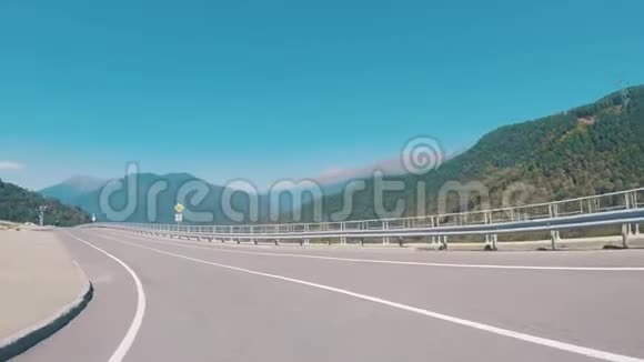 在蓝天上行驶的汽车上一条被树木覆盖的道路和山脉上的风景如画场景山脉视频的预览图