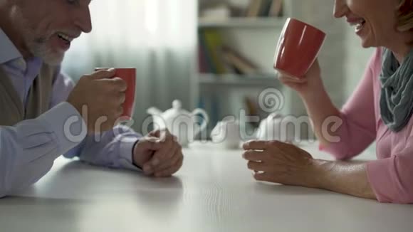 男女退休人员坐在餐桌旁边喝茶边交谈幸福的一对视频的预览图