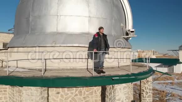 一位成年男性天文台工作人员站在观察穹顶的观察甲板上向远处望去视频的预览图