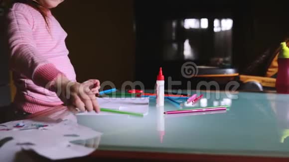 相机左滑动的小可爱的白种人女孩穿着粉红色毛衣用铅笔在桌子上用文具画画视频的预览图