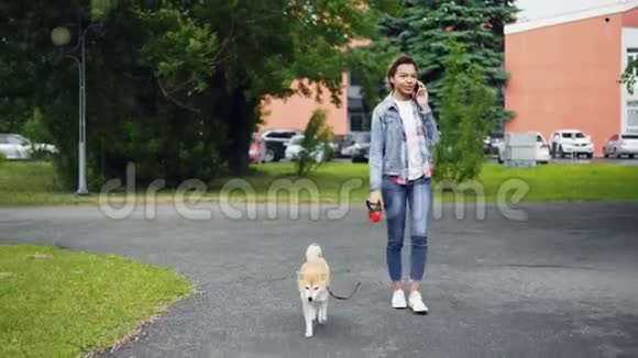 快乐混血女孩在公园里遛狗在手机上和朋友交流现代技术视频的预览图