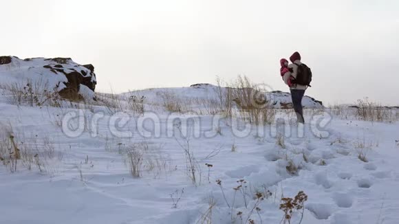 一个年轻人抱着一个孩子在白雪覆盖的小山上暴风雪开始了视频的预览图