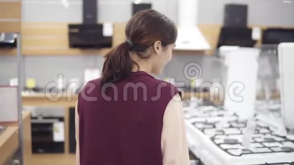 20的年轻女孩在五金店寻找完美的炊具她检查价格打开烤箱视频的预览图