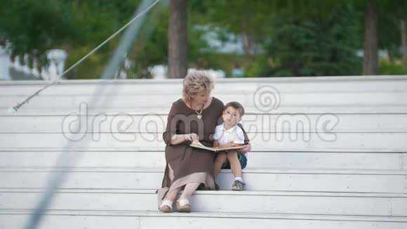 奶奶在公园里给孙子看书晴天视频的预览图
