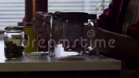 男人手在桌子上用杯子和玻璃茶壶做卷烟视频的预览图