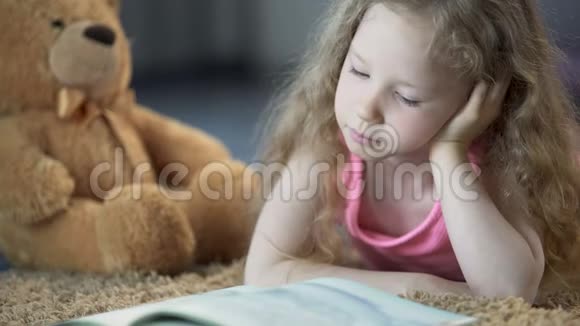 可爱的小女孩专心听童话故事饶有兴趣地读着最喜欢的书视频的预览图