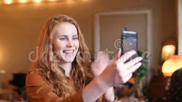 年轻的红发白种人女性智能手机技术视频呼叫咖啡厅视频的预览图