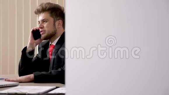 穿着黑色西装和红领带的不耐烦的商人在电话里交谈视频的预览图