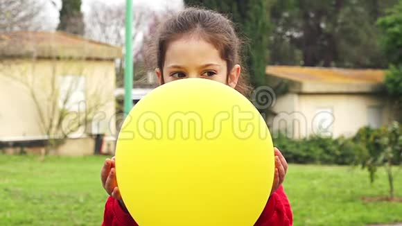 慢动作年轻的女孩拿着一个黄色的气球它会弹出给她带来惊喜视频的预览图