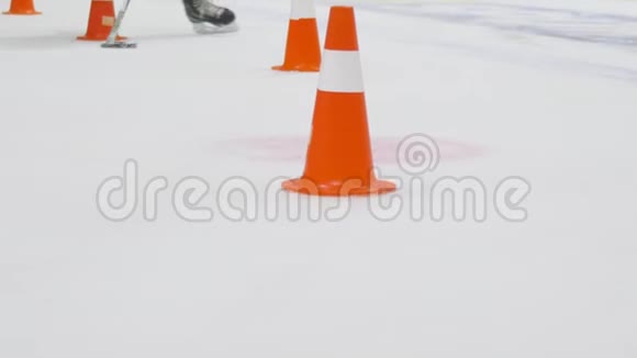 曲棍球训练运动员在溜冰场上用曲棍球棒带领球穿过冰场上的路锥视频的预览图