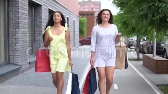 两个漂亮的女朋友在购物后携带不同颜色的包裹慢动作高清高清视频的预览图