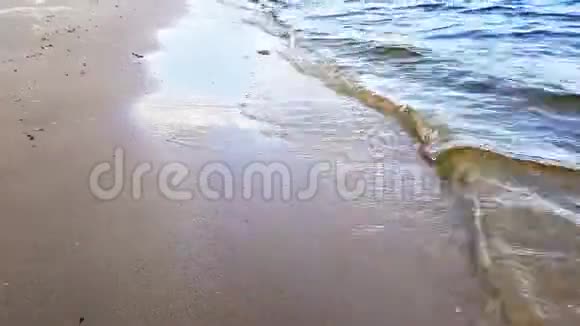 在阳光明媚的日子里小波浪用浅棕色的沙子冲洗河岸视频的预览图