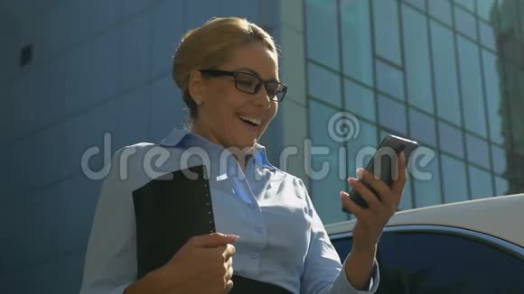 穿西装的女士在智能手机上阅读好消息成功地提升职业生涯视频的预览图