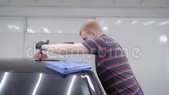 工人用电动工具对汽车维修后的黑色汽车车顶进行打磨视频的预览图