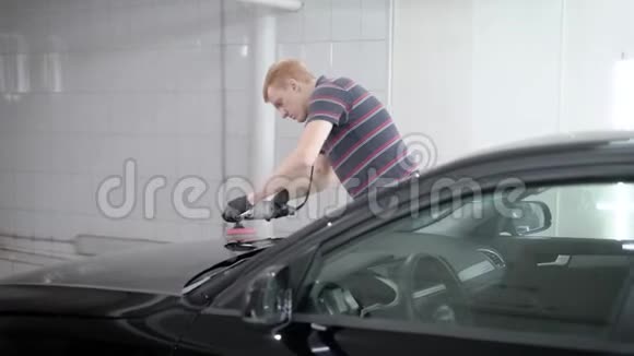 工人正在汽车服务中打磨黑色汽车引擎盖用软抹布擦洗车身视频的预览图