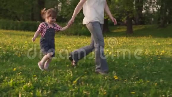 快乐的小女孩和妈妈一起在田野里奔跑阳光明媚的夏日视频的预览图