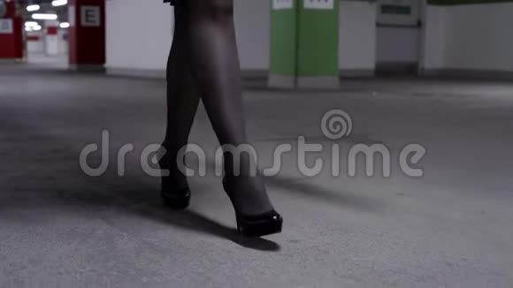 在车库里穿着黑色长袜高跟鞋的行走妇女的双腿视频的预览图