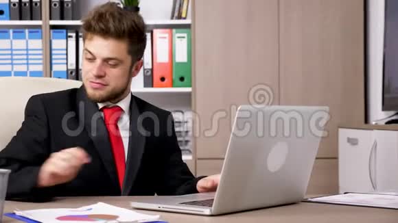 一个穿着正式西装的商人在他的办公桌上给电话视频的预览图