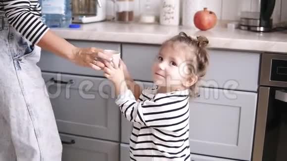 妈妈给女儿一杯水小女孩喝酒妈妈在厨房笑视频的预览图