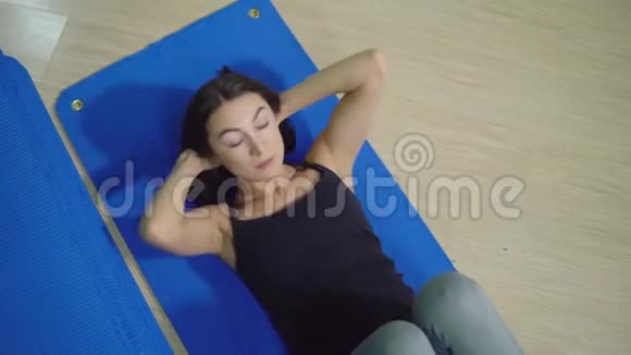 美丽的黑发女人做腹肌锻炼从上面看视频的预览图
