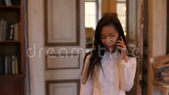 年轻的亚洲女人在咖啡馆里用手机聊天视频的预览图