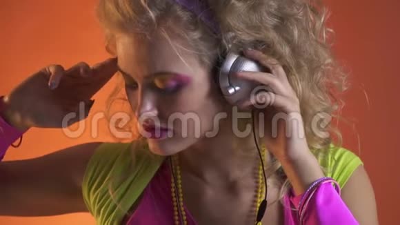 年轻的金发女郎穿着五颜六色的衣服戴着耳机听音乐视频的预览图