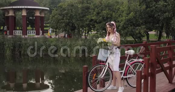 穿着白色裙子的女人坐在公园里看镜头视频的预览图