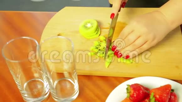 女人用刀子在木板上切熟的猕猴桃视频的预览图
