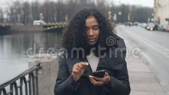 年轻的非洲裔美国黑人妇女步行街在城市4k谈手机视频的预览图