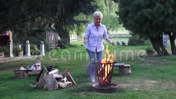 这位年轻女子在篝火旁享受浪漫的夜晚吃烤香肠视频的预览图