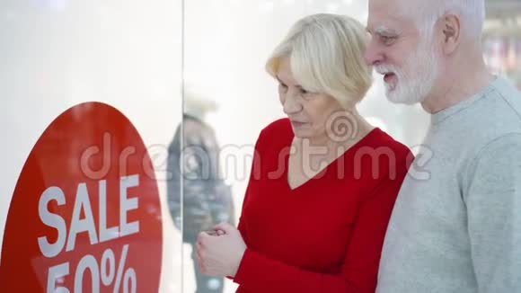 老两口看着橱窗店检查销售价格销售和百分比签名购物中心视频的预览图