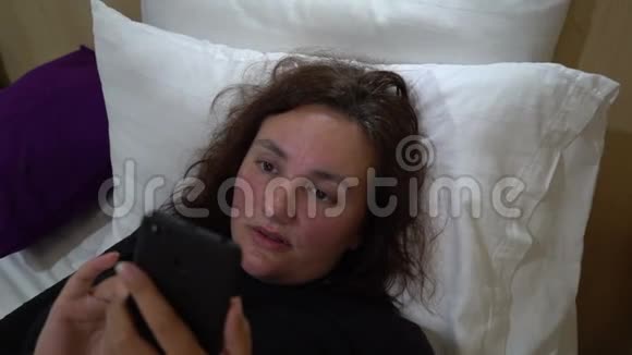 年轻漂亮的女人在床上使用和持有智能手机的不健康习惯使用设备视频的预览图