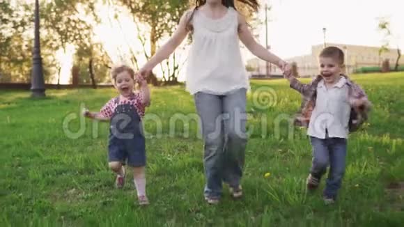 快乐的妈妈和孩子们一起牵着手在公园里跑步视频的预览图
