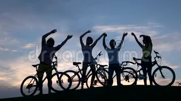 四个欢快的骑自行车的人在夕阳的天空中跳舞视频的预览图