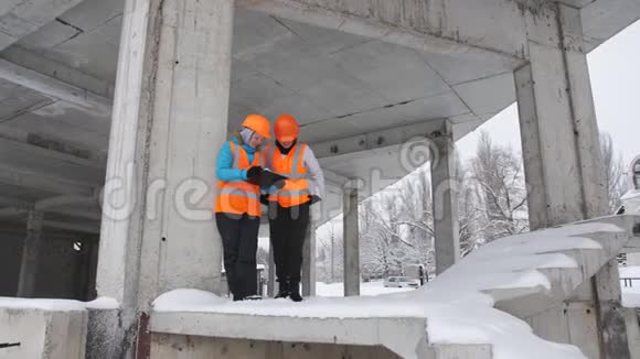 两名女检查员在冬季在施工现场检查和检查施工计划视频的预览图