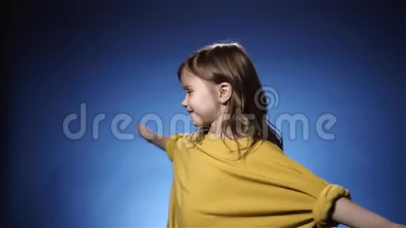 微笑的黄色旋转的小女孩蓝色背景慢动作视频的预览图