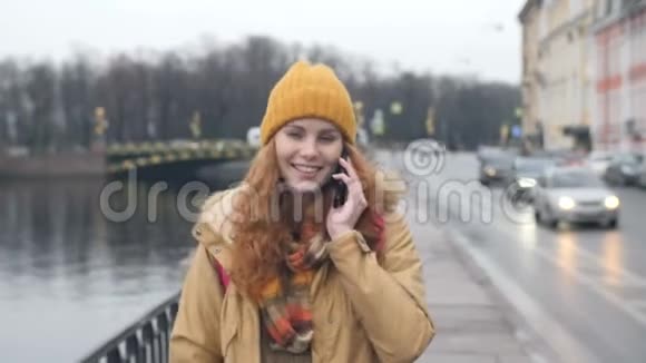 年轻的红头发白种人妇女在城里的大街上谈论手机视频的预览图