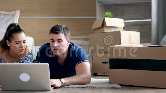 一对夫妇躺在他们的新家网上购物的地板上视频的预览图