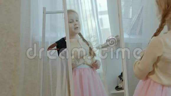 可爱的小女孩梳着粉红色的小辫子把戒指放在镜子前的手上我妈妈的衣柜视频的预览图