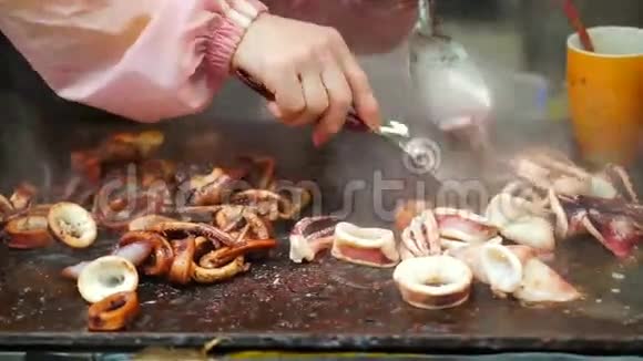 铁板烧烹饪切鱿鱼墨鱼加酱在热盘上视频的预览图
